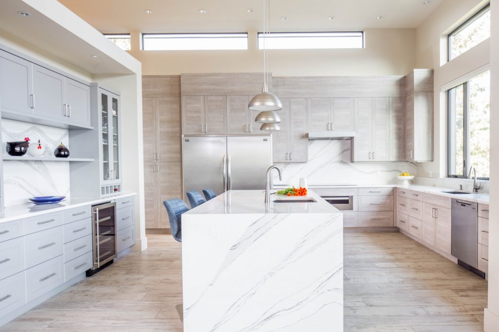 Spacious and well-lit kitchen designed by Westmark's home builders, showcasing a large marble island, sleek cabinetry, and contemporary fixtures.